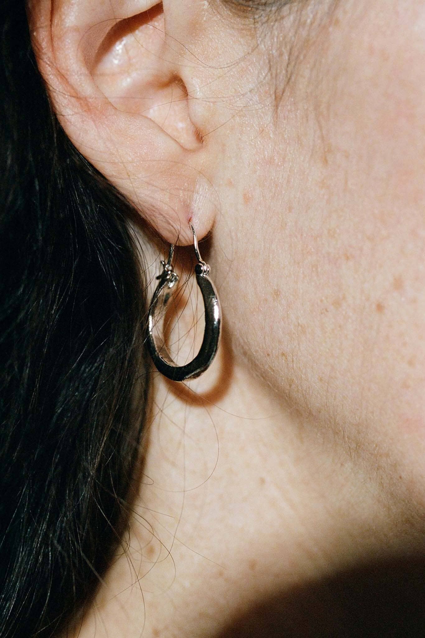 Close-up of a person wearing a silver hoop earring.