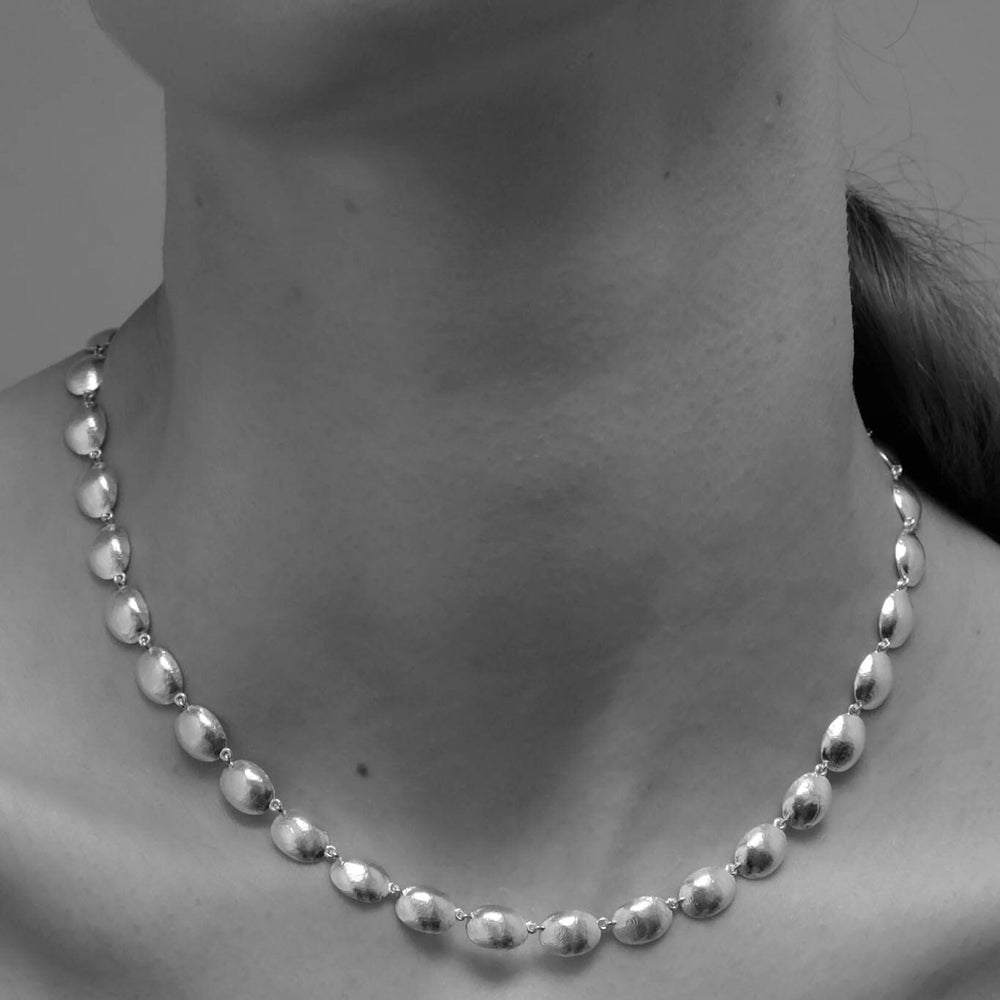 Silver dome necklace on a women against a neutral background