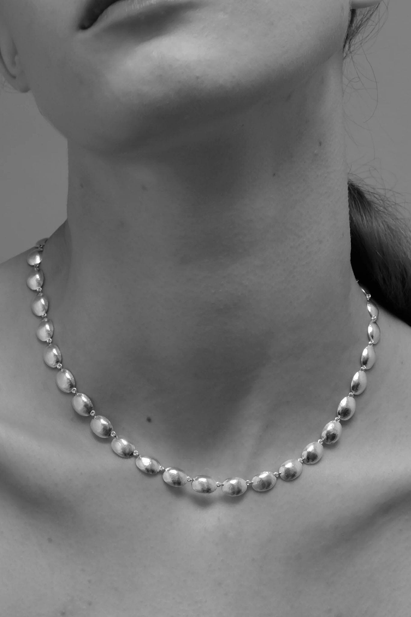 Silver dome necklace on a women against a neutral background