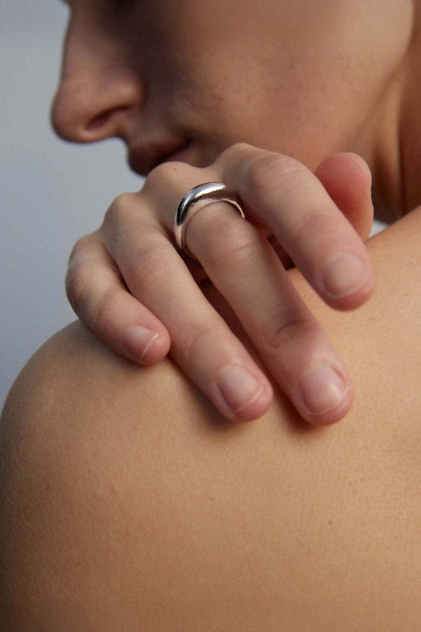 Close-up of a hand with a silver dome ring on a blurred background