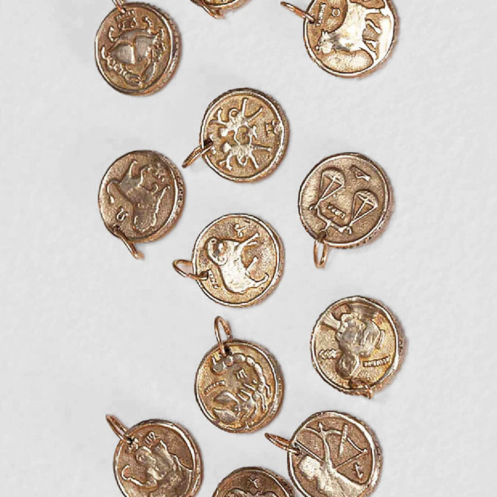 Brass zodiac charm coins by Alexis Laurel. Available to purchase at M.patmos.