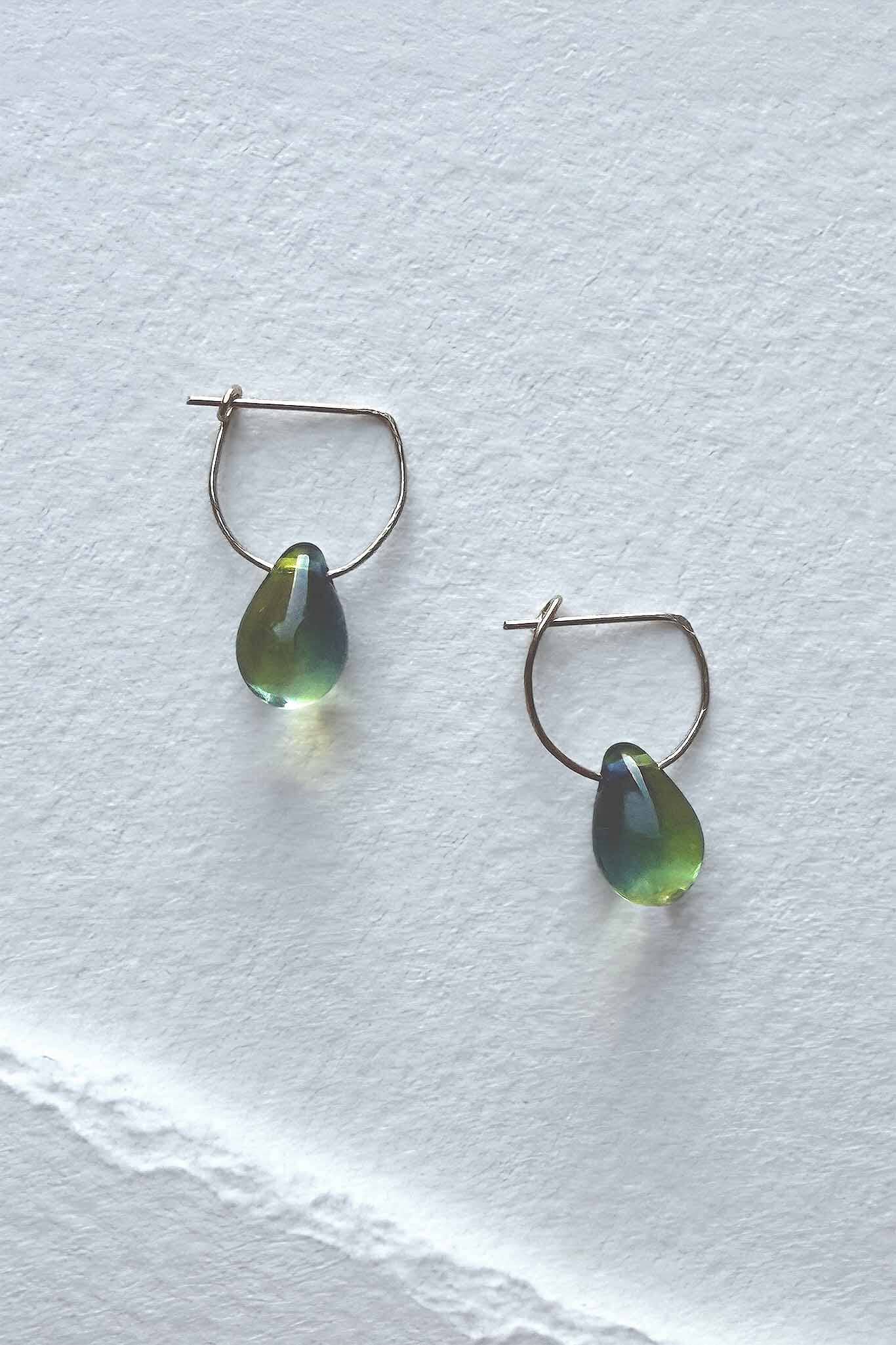 Pair of green glass teardrop hoop earrings on a white background