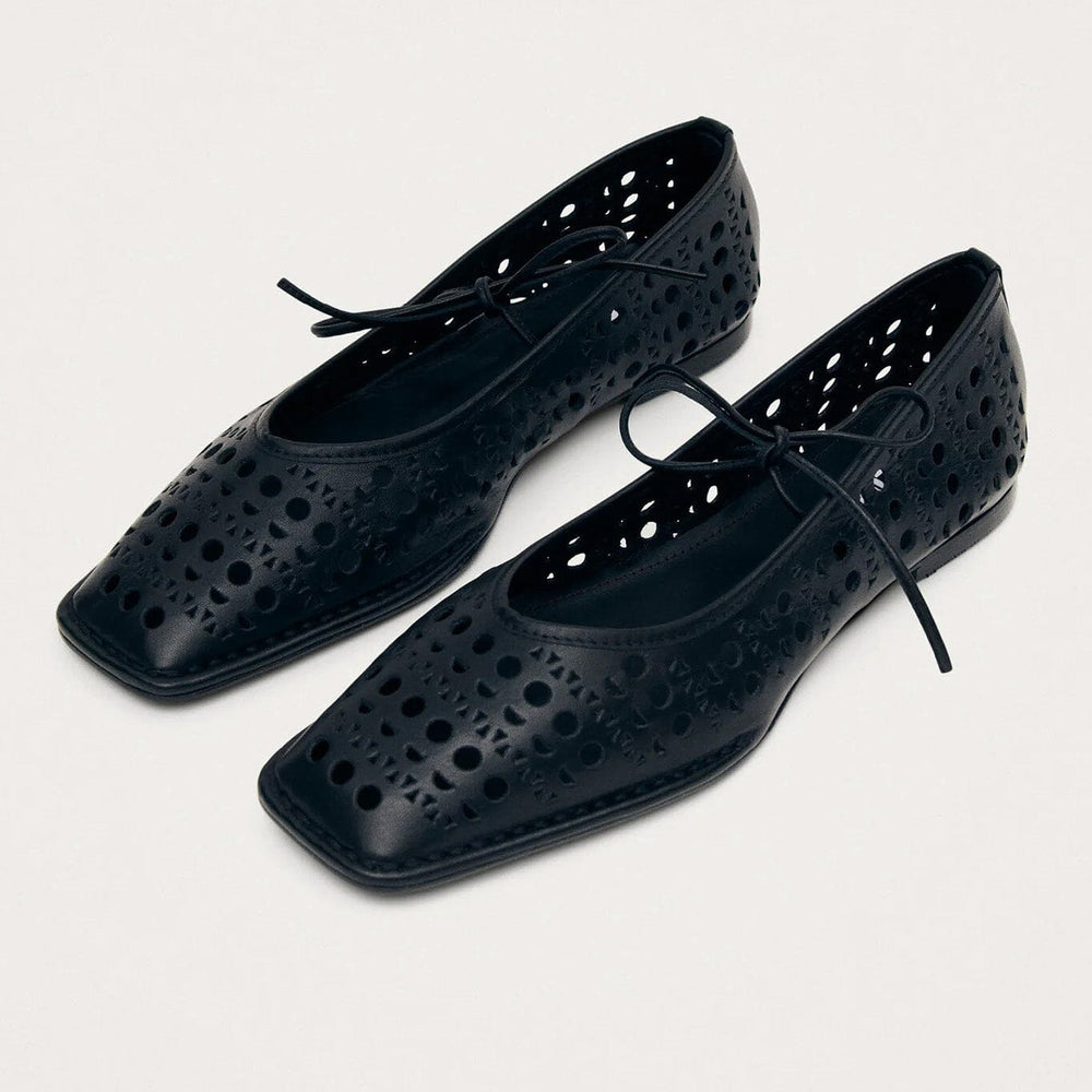 
                  
                    A pair of black leather ballet flats with laser-cut patterns and a bow detail on top
                  
                