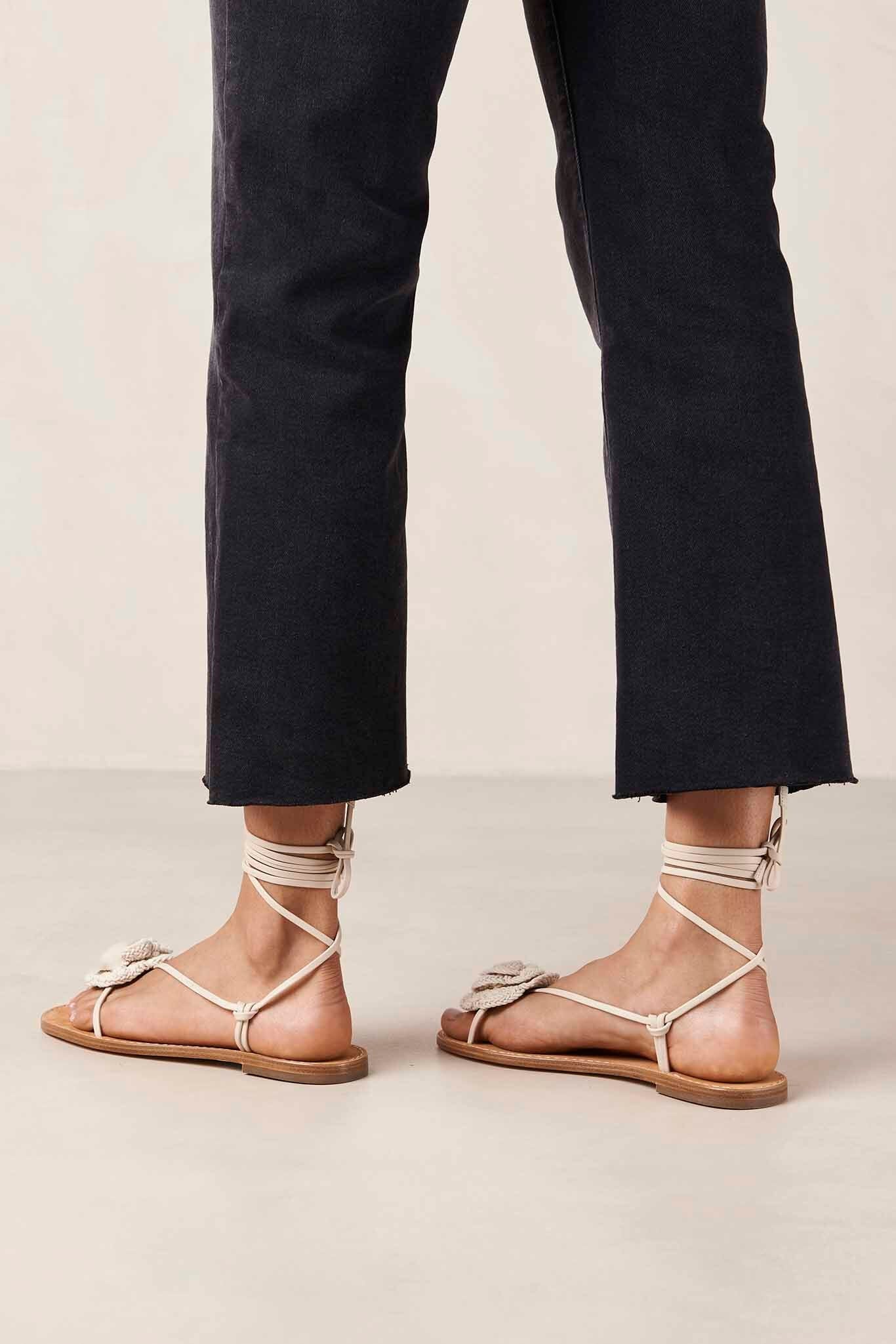 The back view of cream-colored leather sandals with crocheted flowers and minimal straps