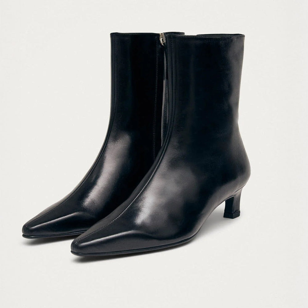 Pair of black heeled ankle boots on a light gray background