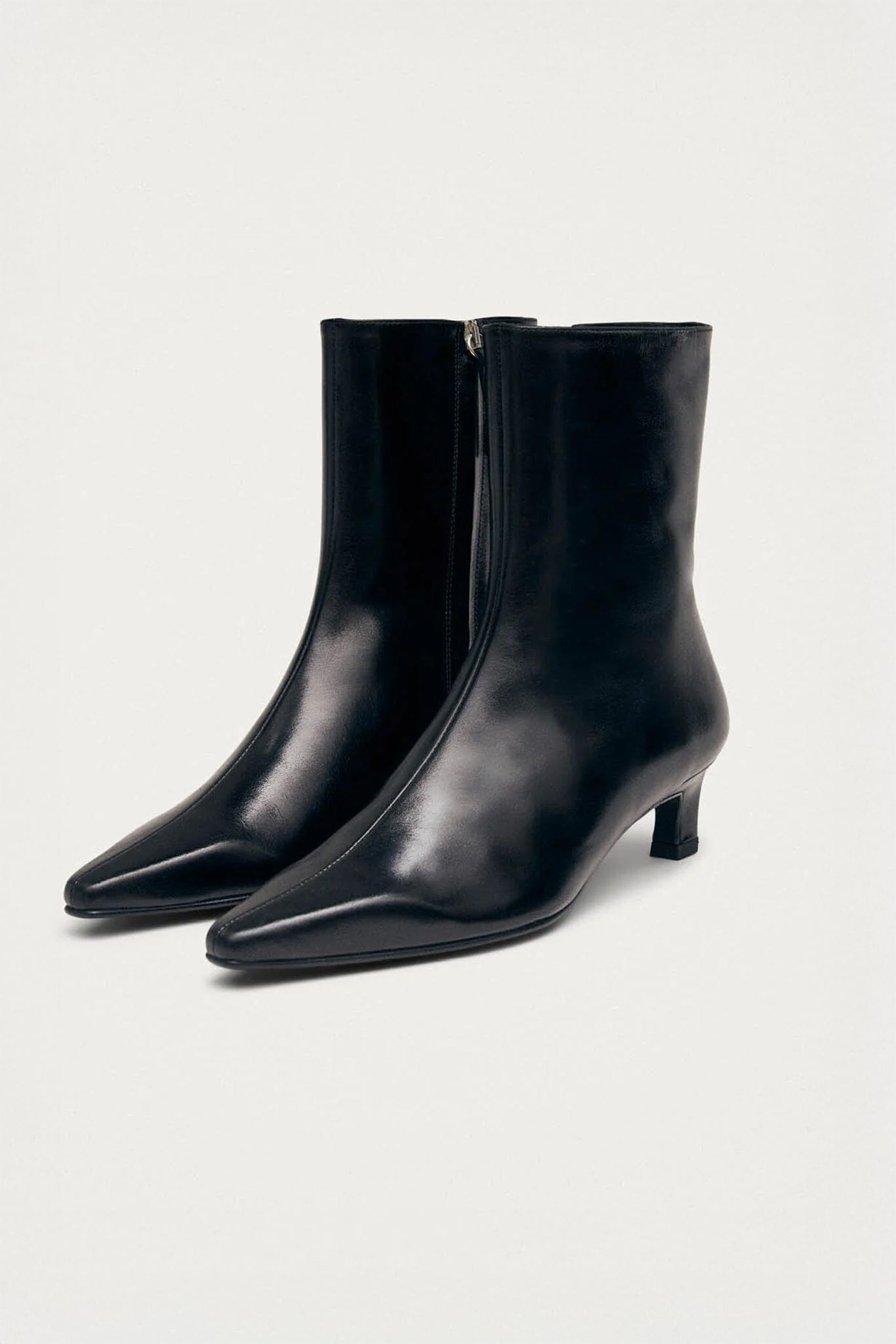 Pair of black heeled ankle boots on a light gray background