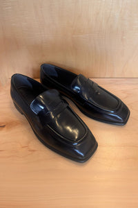 Pair of black loafers on a wooden surface
