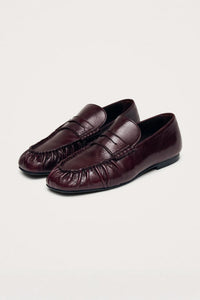 Pair of burgundy loafers on a light beige background