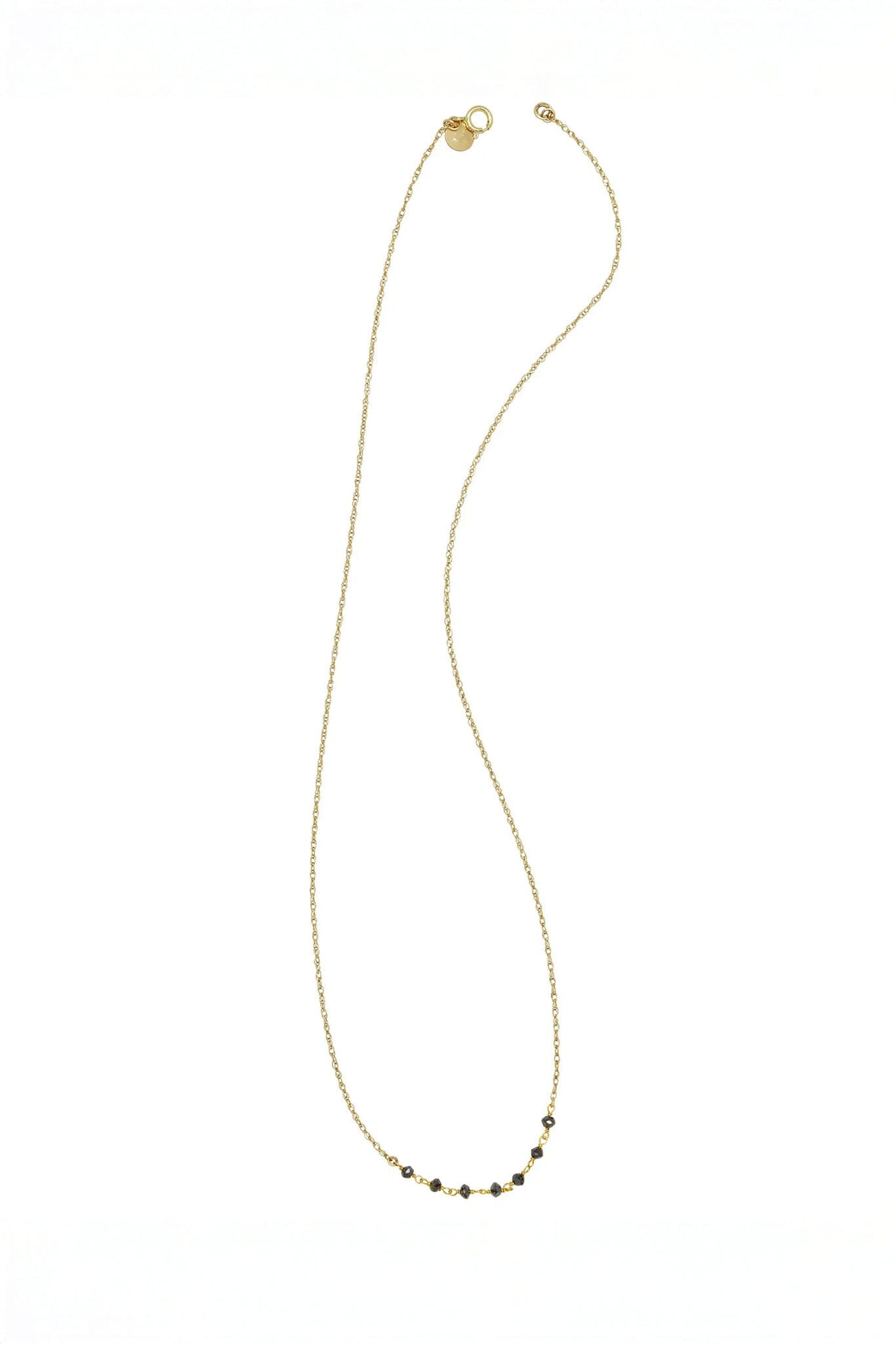 Gold necklace with small black diamond beads on a white background