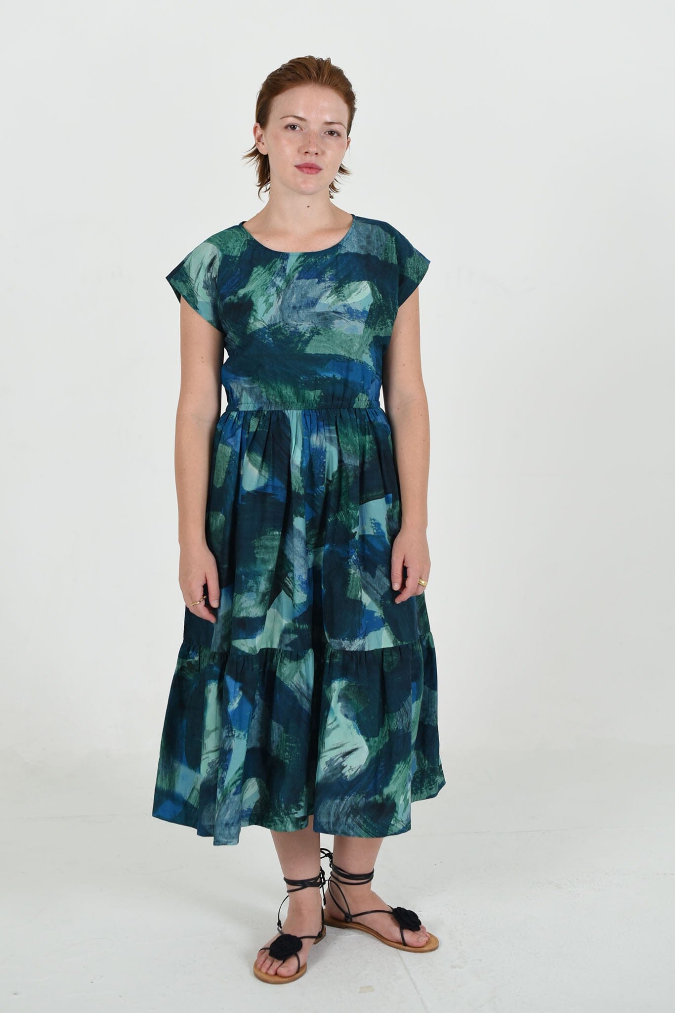 The large M.PATMOS Penelope Dress in Blue Abstract, features a button-down front, midi-length silhouette, waist belt for shaping, and an eye-catching abstract print in blue tones.