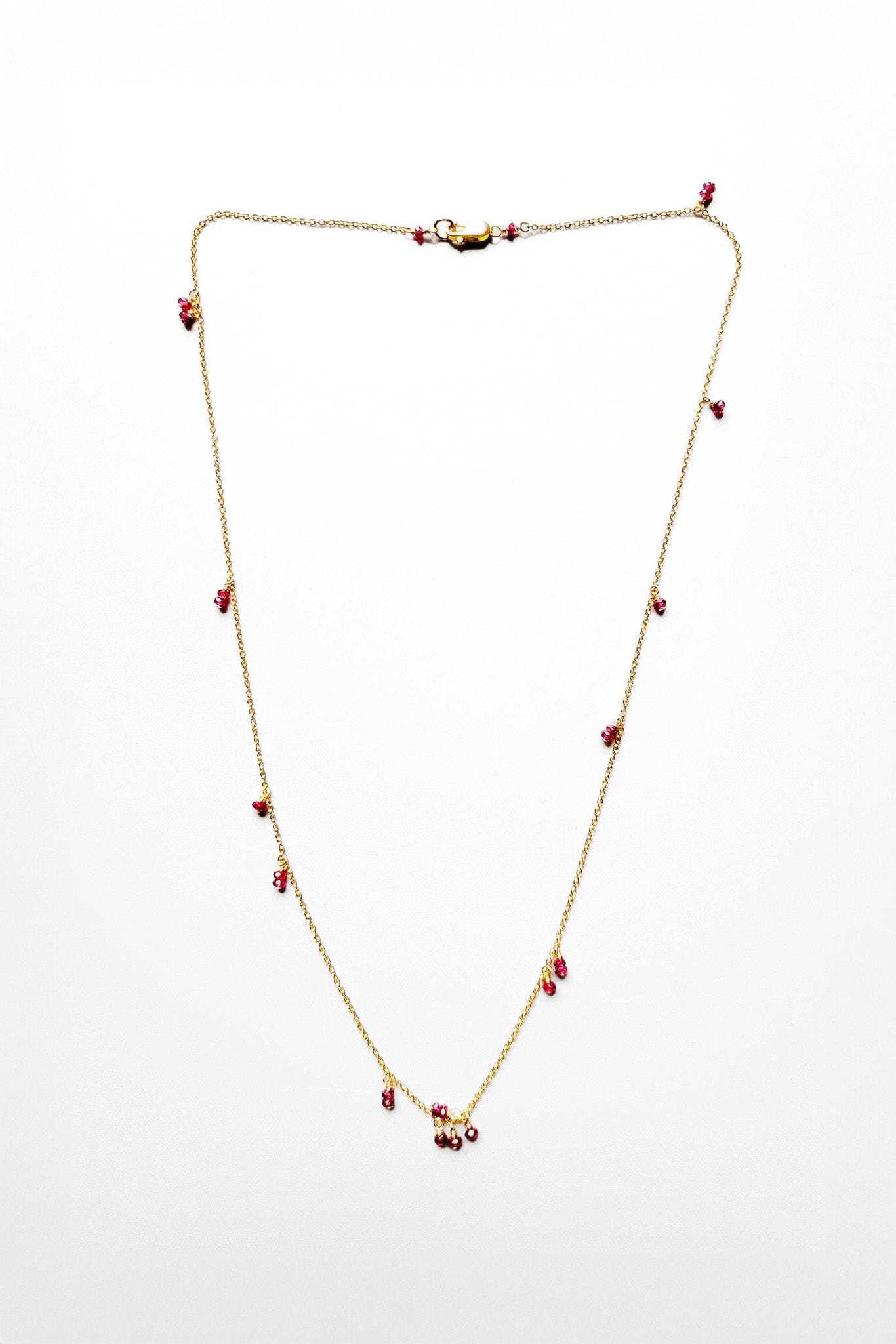 A delicate 14k gold filled chain necklace with cairn-like ruby briolettes on a white background.