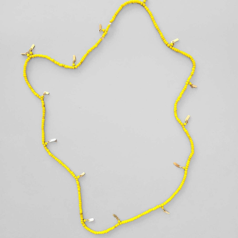 A vintage yellow necklace with gold "Bali" tassle beads, displayed against a white background.