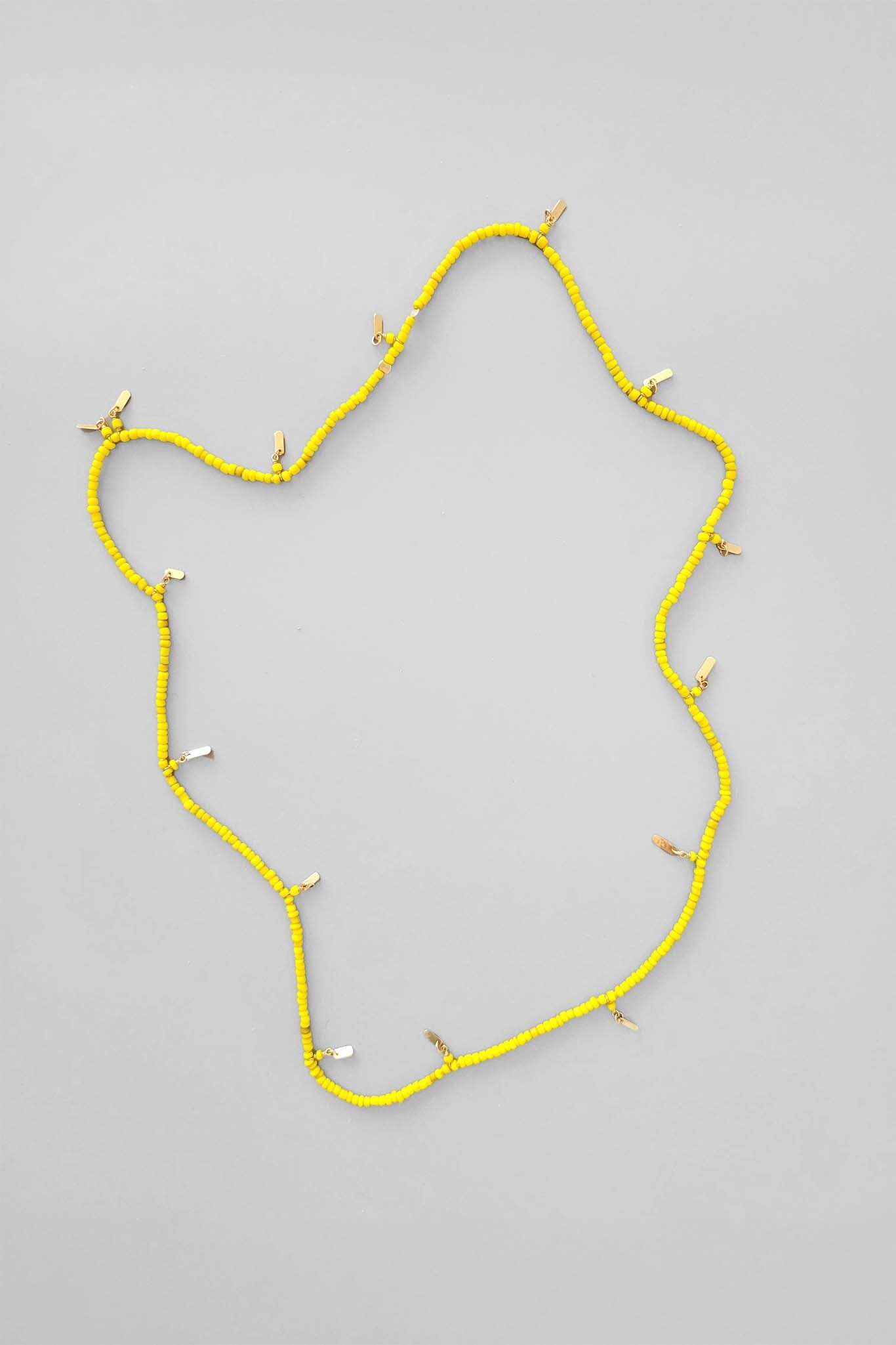 A vintage yellow necklace with gold "Bali" tassle beads, displayed against a white background.