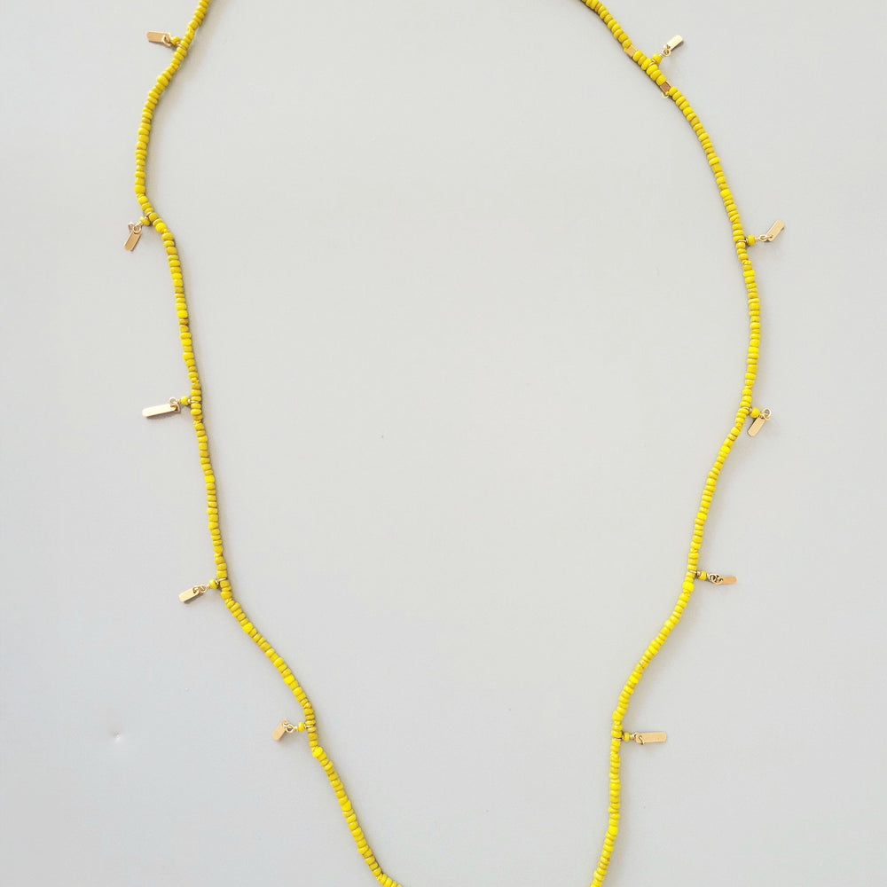 Yellow beaded necklace on a light gray background