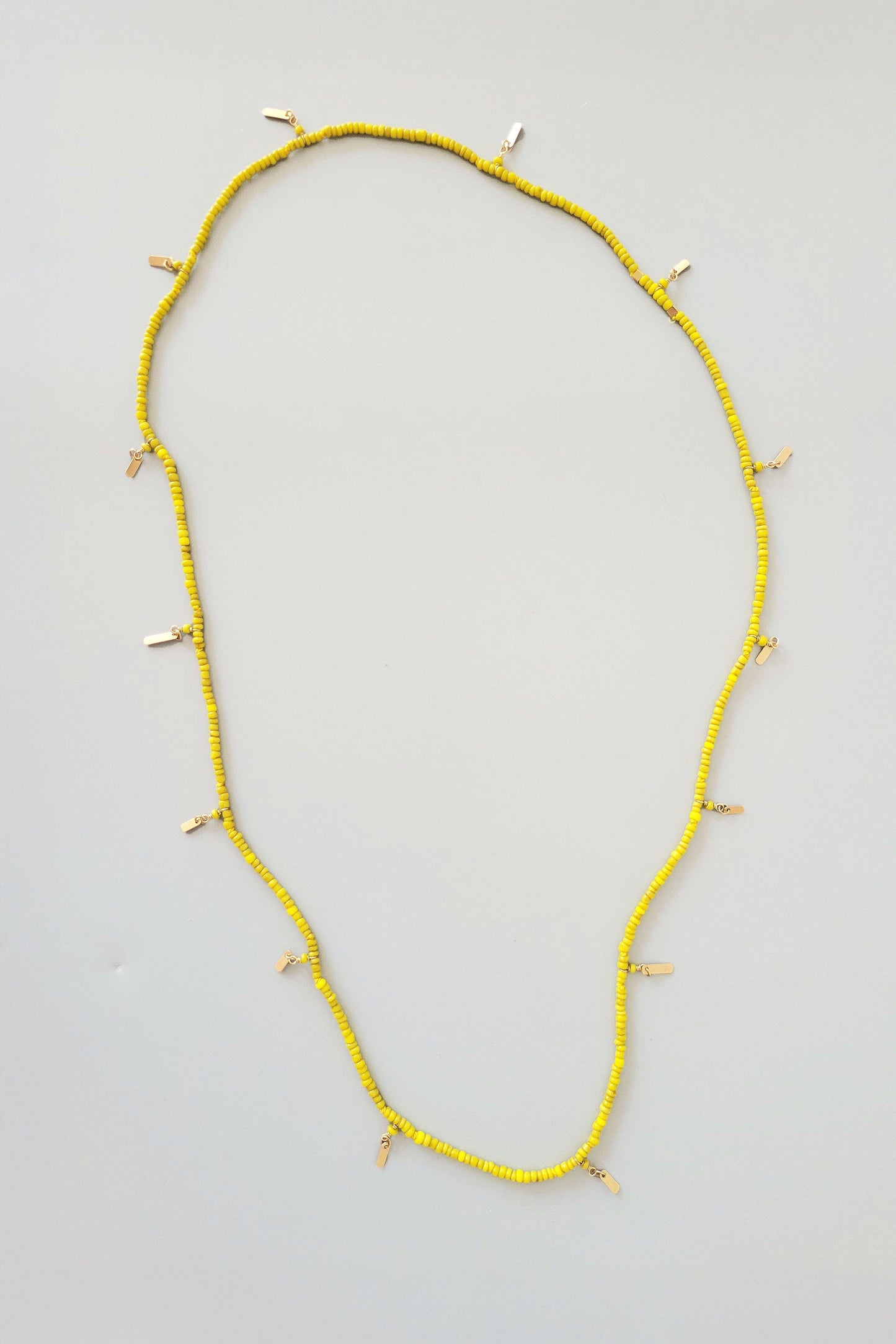 Yellow beaded necklace on a light gray background