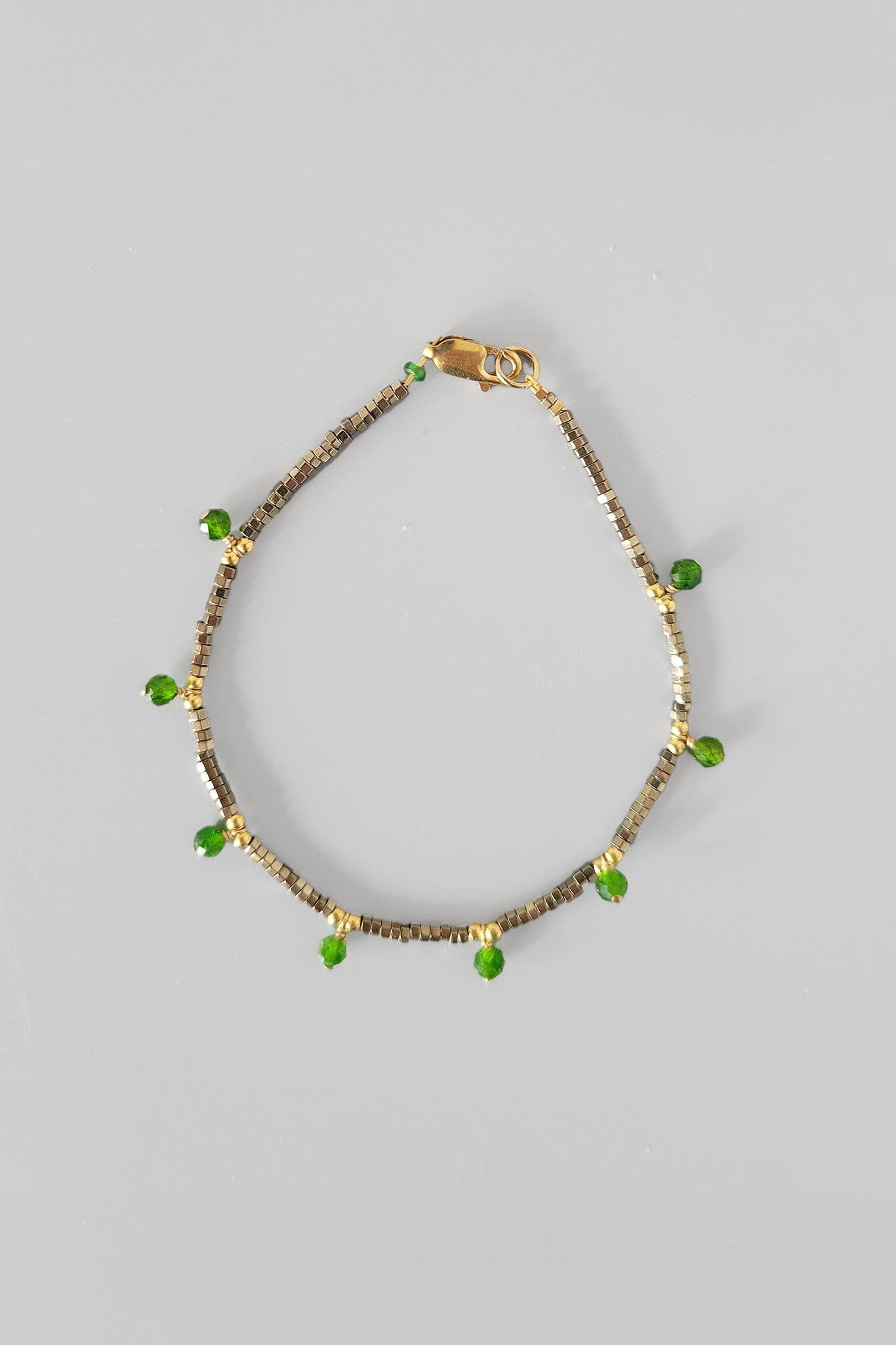 Bracelet with green beads on a gray background