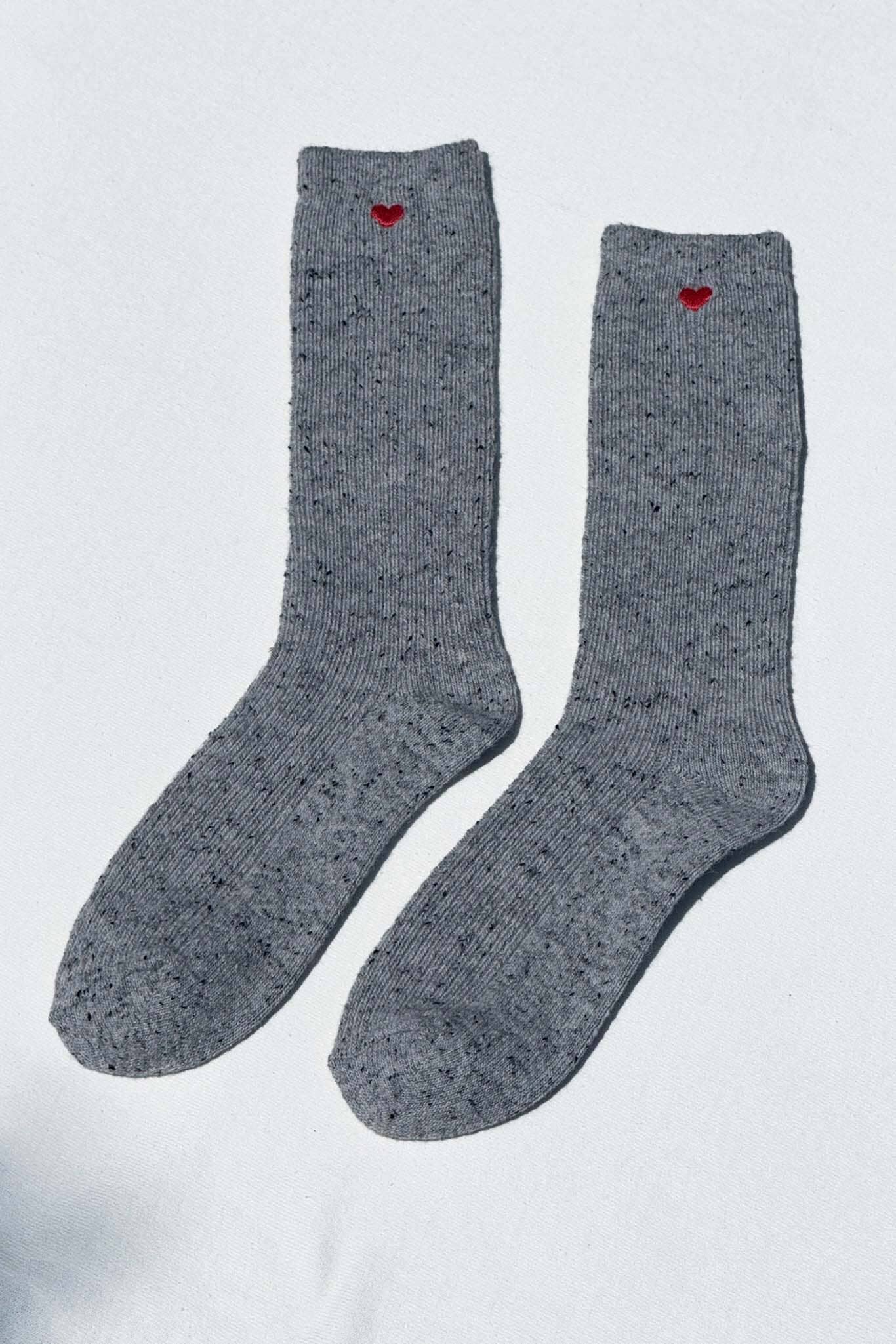 Pair of gray socks with red hearts on a light gray background