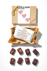 Box of fine and raw chocolate with a card and chocolates on a white background