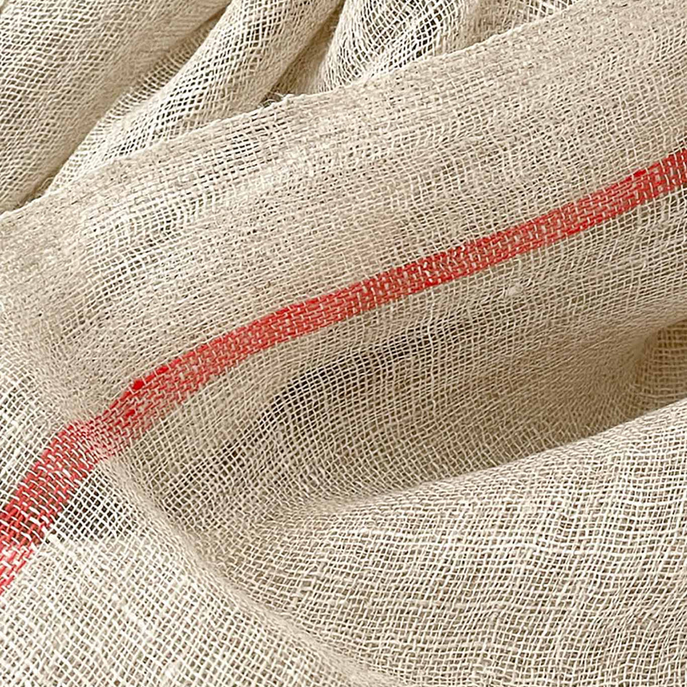 A detailed shot of a handwoven scarf in oatmeal color with orange stripes