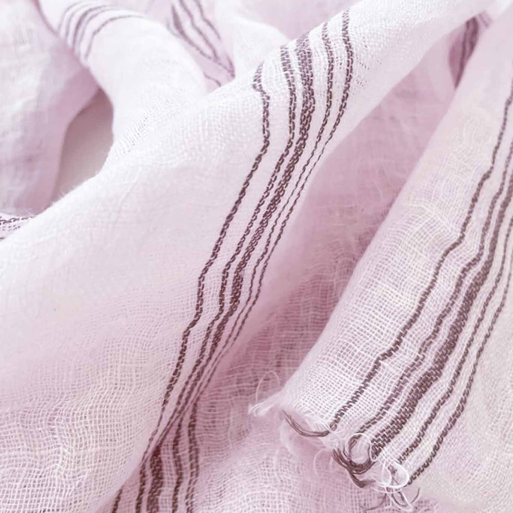 Detailed shot of a handwoven scarf in lilac color with striped patterns, made of linen