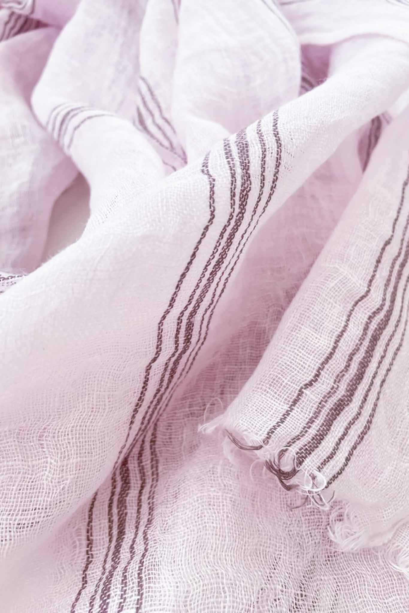 Detailed shot of a handwoven scarf in lilac color with striped patterns, made of linen