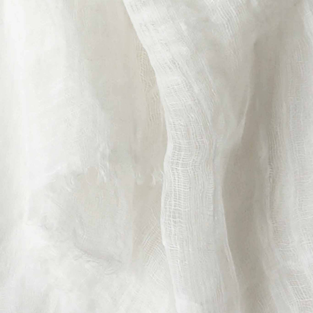 A close up shot of a handwoven, airy white scarf made of linen