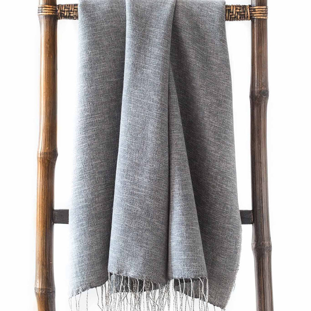 
                  
                    A gray Turi scarf with fringe hanging on a bamboo ladder.
                  
                
