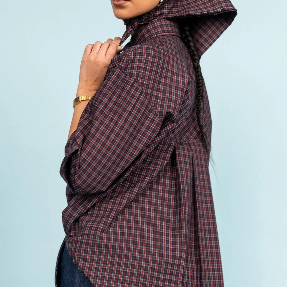 Person wearing a plaid shirt and scarf against a light blue background