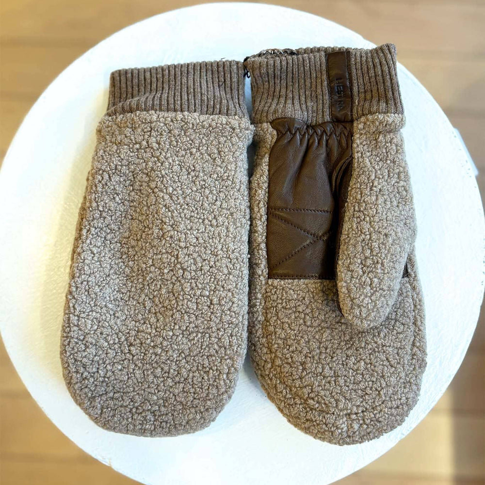 Pair of brown fleece mittens on a white plate with a wooden background
