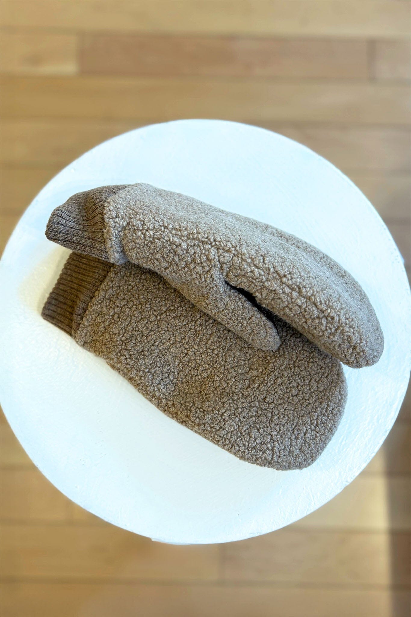 Pair of brown fleece mittens on a white background