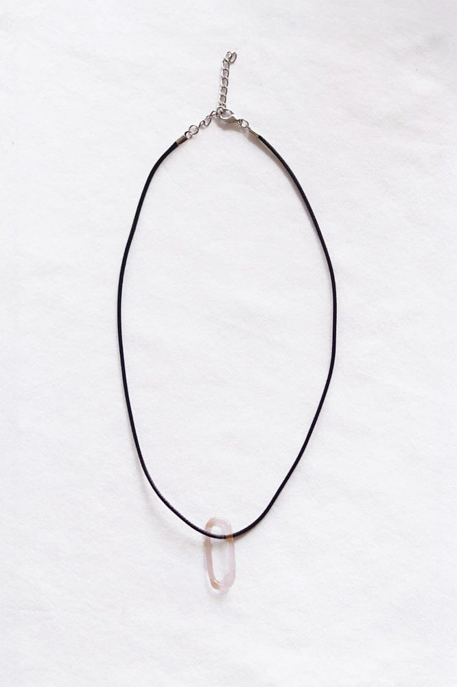 Black cord necklace with a light pink oval glass pendent on a white background