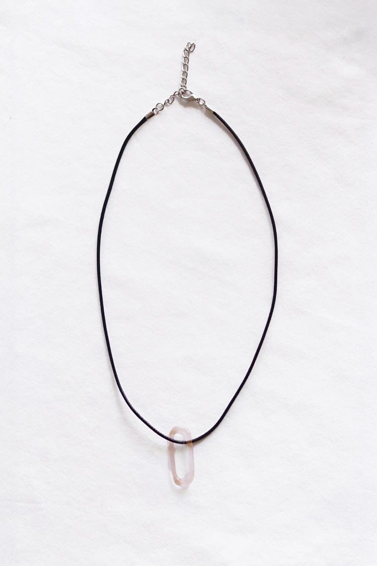 Black cord necklace with a light pink oval glass pendent on a white background