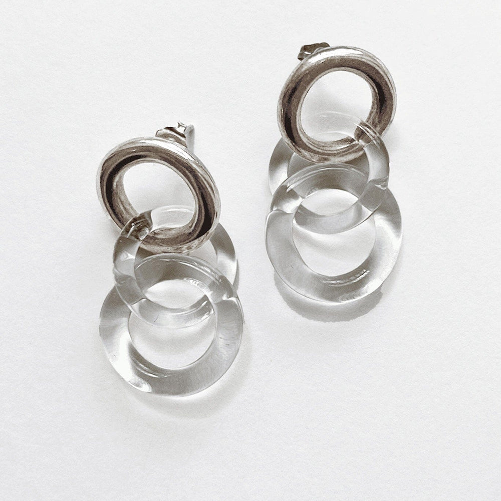 A pair of silver circle stud earrings with two clear glass chain links, displayed against a white background.