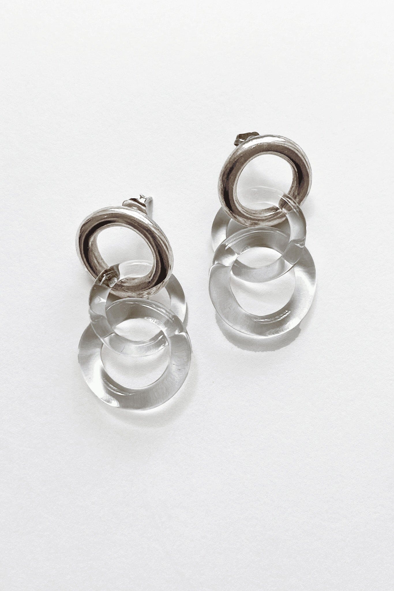 A pair of silver circle stud earrings with two clear glass chain links, displayed against a white background.