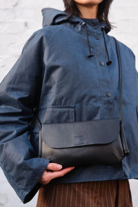 Model wearing the London-designed Kate Sheridan Black Ribbon Bag. A sleek black leather crossbody for everyday use.