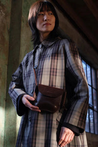 Model wearing the London-designed Kate Sheridan Date Mini Ribbon Bag. A stylish dark brown leather crossbody.