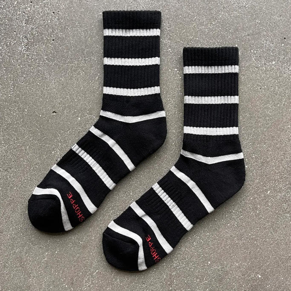 A pair of black striped socks with white stripes, laid out flat on a surface.