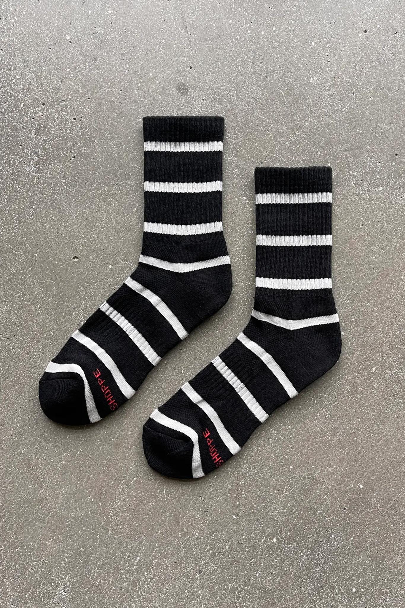 A pair of black striped socks with white stripes, laid out flat on a surface.