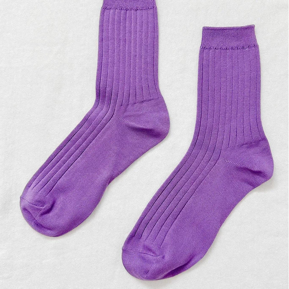 A pair of violet colored, ribbed, ankle-high socks displayed against a white background.