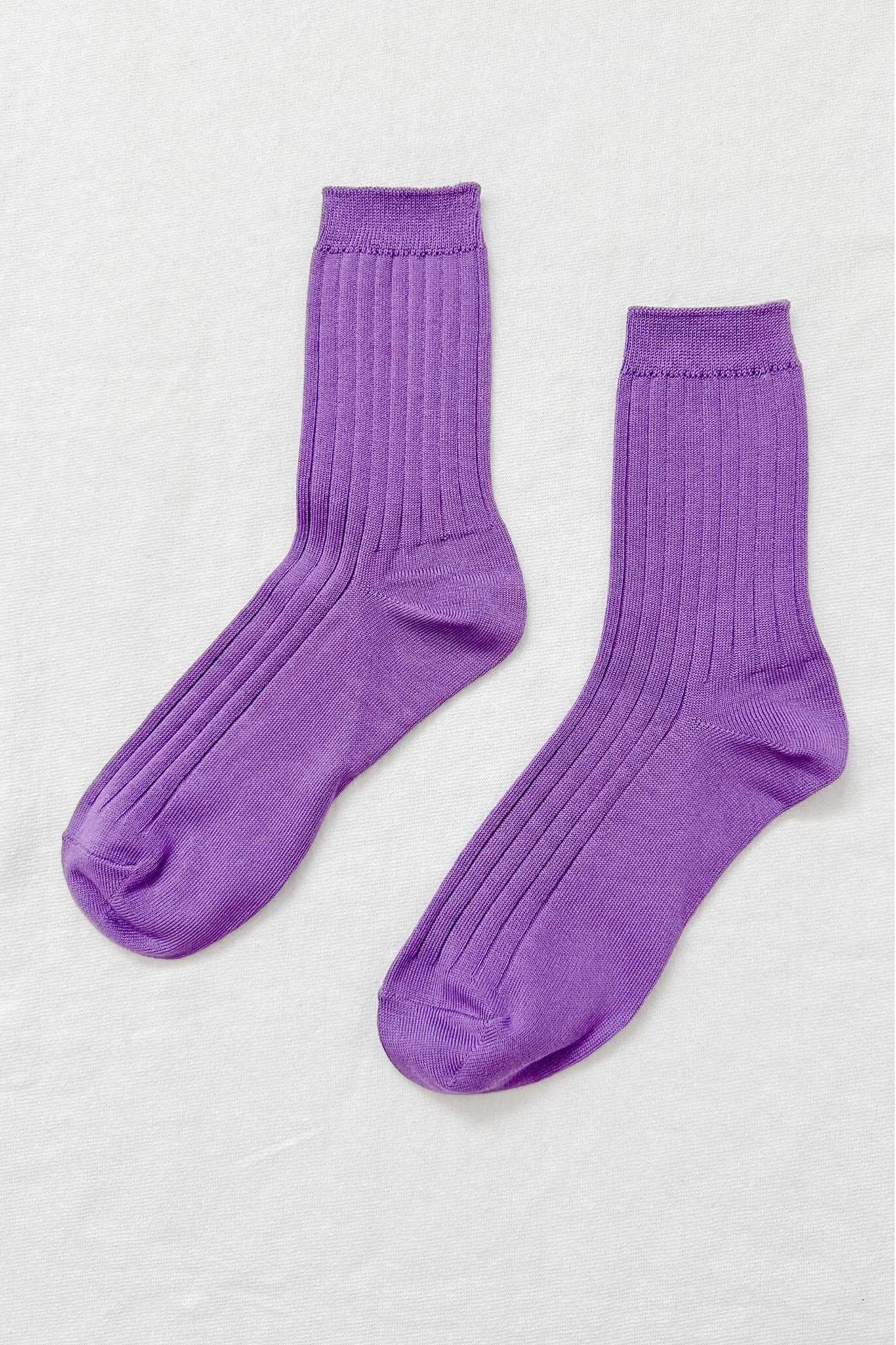 A pair of violet colored, ribbed, ankle-high socks displayed against a white background.