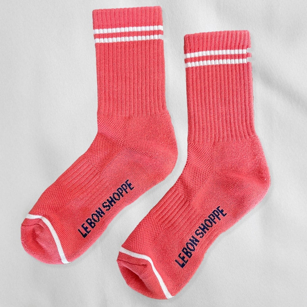 A pair of calf-length coral pink socks with white stripes and the text 'LE BON SHOPPE' on the side.