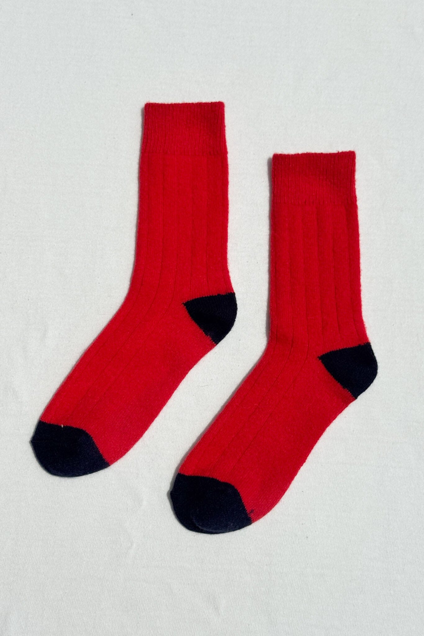 Pair of red socks with black toes and heels on a light gray background