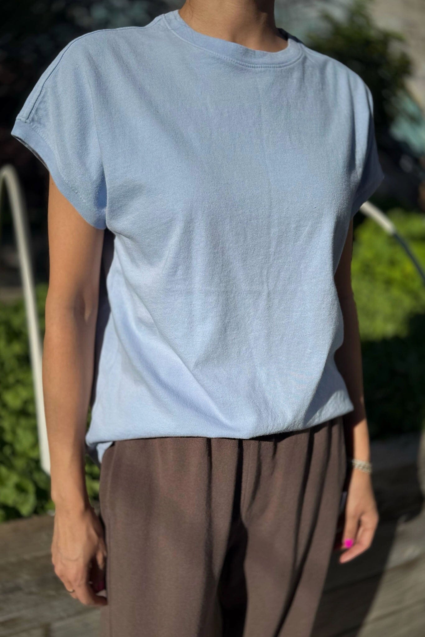 Person wearing a light blue t-shirt and brown pants outdoors