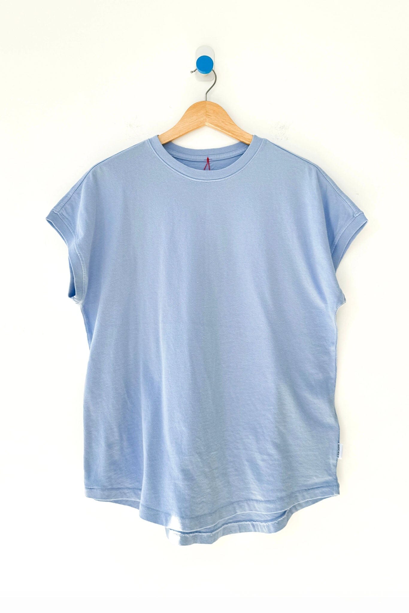 Light blue t-shirt on a wooden hanger against a white background