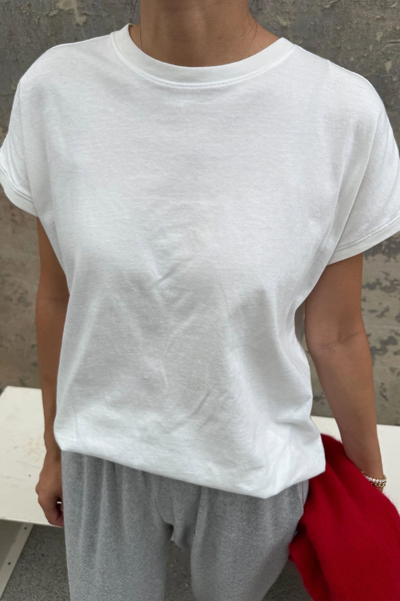 Person wearing a plain white t-shirt and gray pants against a neutral background