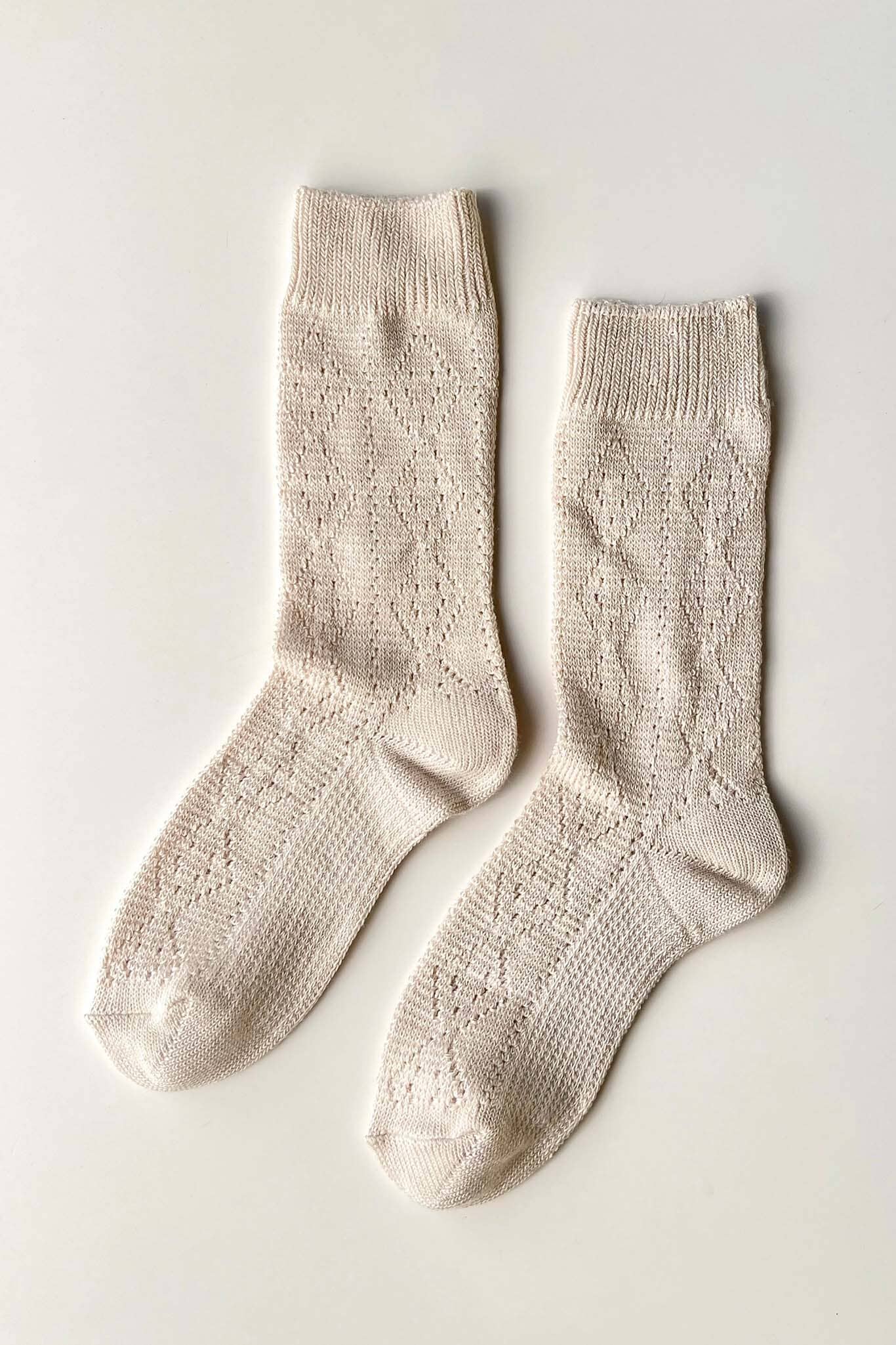 Pair of beige socks on a light gray background