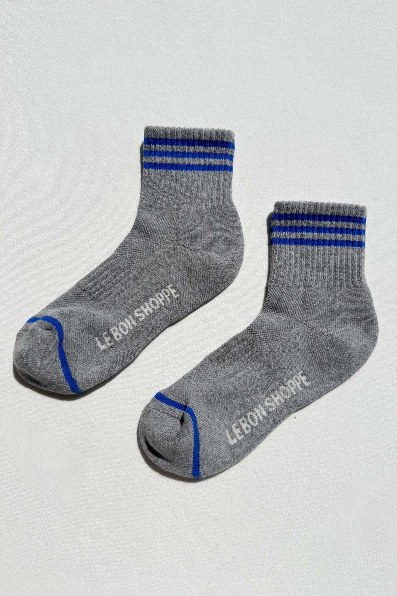 Gray socks with blue stripes and 'Le Bon Shoppe' branding on a light gray background