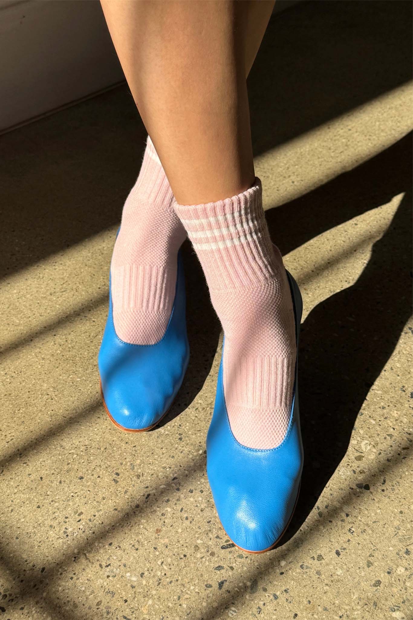 Blue shoes and pink socks on a concrete surface