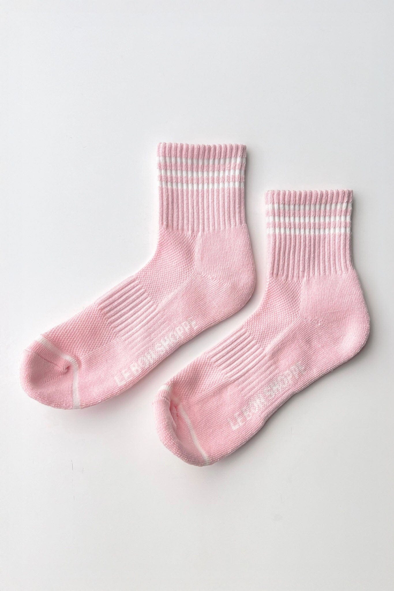 Pair of pink socks with white stripes on a light gray background