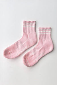 Pair of pink socks with white stripes on a light gray background